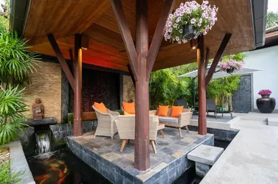 an outdoor living area with a koi pond and a pergola at The Thara Villa Surin Beach in Surin Beach