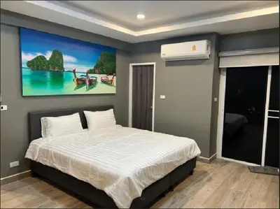 a bedroom with a bed with a painting on the wall at Patong Vacation Rentals - Located in the Heart of Patong, Studio Apartments walking distance to the beach, King Bed, Kitchen, Private Bathroom, Seating Area, 65