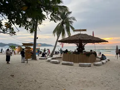 a group of people on a beach with an umbrella at Patong Vacation Rentals - Located in the Heart of Patong, Studio Apartments walking distance to the beach, King Bed, Kitchen, Private Bathroom, Seating Area, 65