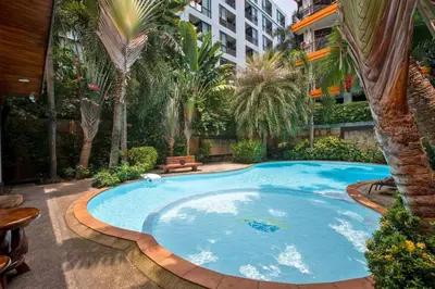 a large swimming pool in a courtyard with palm trees at New Condo NaiHarn Beach by Capital Pro in Phuket Town