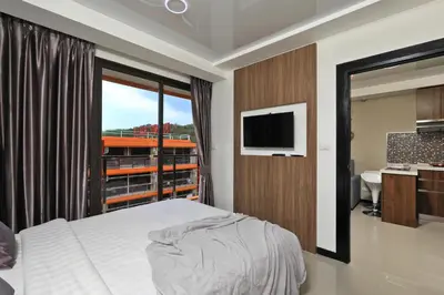 a bedroom with a bed and a window and a television at Naiharn Sea Condo by Capital Pro in Phuket Town