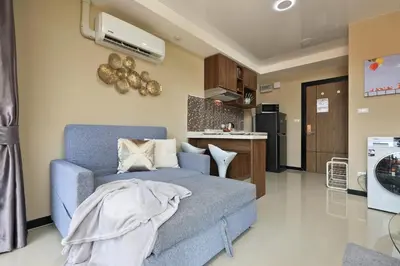a living room with a blue couch and a kitchen at Naiharn Sea Condo by Capital Pro in Phuket Town