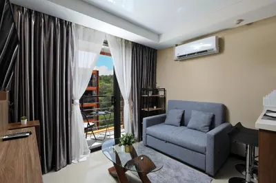 a living room with a couch and a window at 1bdr Apartment Naiharn Beach Condo by CapitalPro in Phuket Town