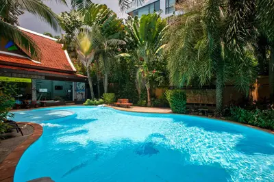 a large blue swimming pool in a yard with palm trees at 1bdr Apartment Naiharn Beach Condo by CapitalPro in Phuket Town