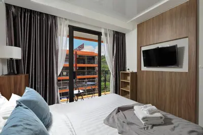 a bedroom with a bed and a tv and a window at 1bdr Apartment Naiharn Beach Condo by CapitalPro in Phuket Town