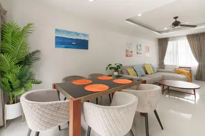 a living room with a table and chairs and a couch at Welcoming 3bdr Townhouse Laguna Park in Ban Phru Champa