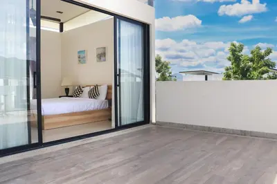 a bedroom with sliding glass doors and a bed on a balcony at Welcoming 3bdr Townhouse Laguna Park in Ban Phru Champa