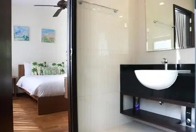 a bathroom with a sink and a mirror and a bed at Welcoming 3bdr Townhouse Laguna Park in Ban Phru Champa