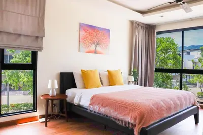 a bedroom with a large bed with yellow pillows at Welcoming 3bdr Townhouse Laguna Park in Ban Phru Champa