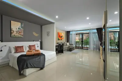 a bedroom with a white bed and a living room at 1bdr Pool Access Studio on NaiHarn Beach by Capital Pro in Phuket Town