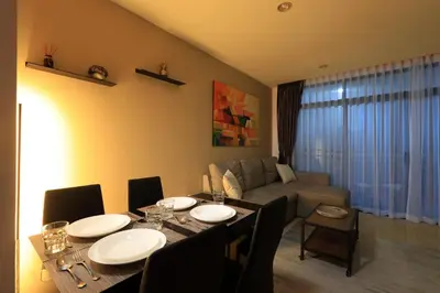 a living room with a table and a couch at 1bdr Pool Access Studio on NaiHarn Beach by Capital Pro in Phuket Town