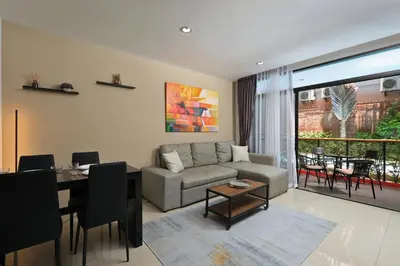 a living room with a couch and a table at 1bdr Pool Access Studio on NaiHarn Beach by Capital Pro in Phuket Town