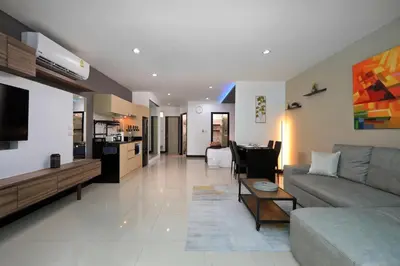 a living room with a couch and a kitchen at 1bdr Pool Access Studio on NaiHarn Beach by Capital Pro in Phuket Town