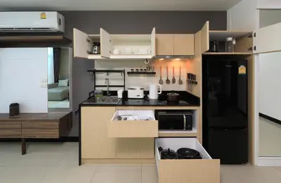 a small kitchen with brown cabinets and a black refrigerator at 1bdr Pool Access Studio on NaiHarn Beach by Capital Pro in Phuket Town