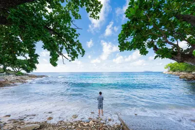 a person standing on the beach looking out at the ocean at Ban Raya Resort and Spa in Ko Racha Yai