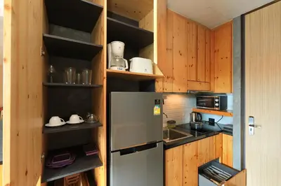a kitchen with a stainless steel refrigerator and wooden cabinets at 1bdr Apartment ReLife Windy Naiharn by CapitalPro in Phuket Town