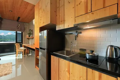 a kitchen with wooden cabinets and a stainless steel refrigerator at 1bdr Apartment ReLife Windy Naiharn by CapitalPro in Phuket Town