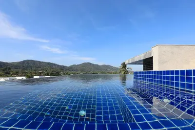 a swimming pool with blue tiles on the water at 1bdr Apartment ReLife Windy Naiharn by CapitalPro in Phuket Town