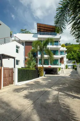 a white building with palm trees in front of it at 1bdr Apartment on the Kata Beach SPL-101 by Capital Pro in Phuket Town