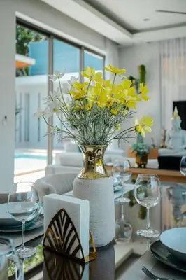 a vase filled with yellow flowers on a table at Villa Mimosa 2, Splendid 3 Bedroom Master Ensuite in Phuket Town