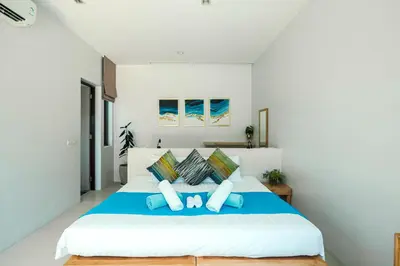 a bedroom with a large bed with blue pillows at Villa Mimosa 2, Splendid 3 Bedroom Master Ensuite in Phuket Town