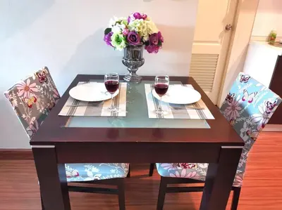 a table with two glasses of wine and a vase of flowers at Best Location Patong Near Jungceylon + Pool Access in Patong Beach