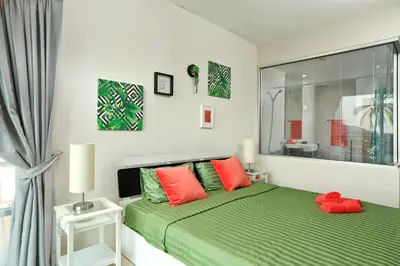 a bedroom with a green bed with red pillows at 1bdr Apartment with bath in Chic Condo By Capital Pro in Phuket Town