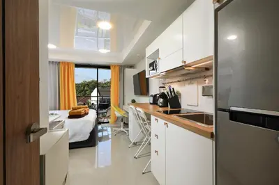 a kitchen with white cabinets and a bed in a room at New apartment Rawai Beach 218 by Capital Pro in Phuket Town
