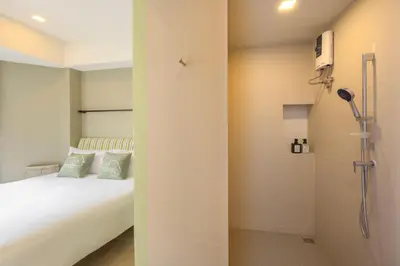 a bedroom with a white bed and a shower at Chamemon Bed Phuket Town in Phuket Town