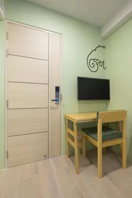 a room with a desk and a tv and a door at Chamemon Bed Phuket Town in Phuket Town