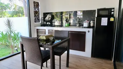 a table and chairs in a kitchen with a refrigerator at Jasmine Village in Rawai Beach