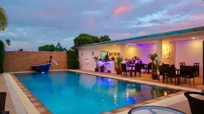a swimming pool in a backyard with a table and chairs at Jasmine Village in Rawai Beach