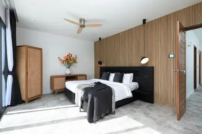 a bedroom with a large bed with a wooden wall at New 4 bedroom pool villa in Rawai by Capital Pro in Phuket Town