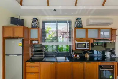 a kitchen with wooden cabinets and a black counter top at 3bdr VIP Villa Rawai with private pool in Phuket Town