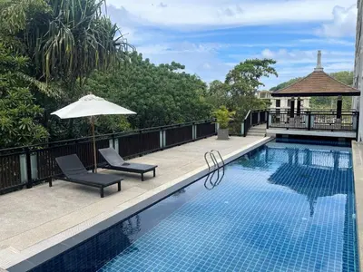 a swimming pool with two chairs and an umbrella at Spacious apartment Kamala Falls by Lofty in Kamala Beach