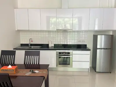 a kitchen with white cabinets and a table and a sink at Spacious apartment Kamala Falls by Lofty in Kamala Beach