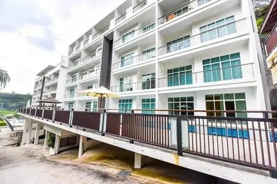 a white building with a balcony and an umbrella at Spacious apartment Kamala Falls by Lofty in Kamala Beach