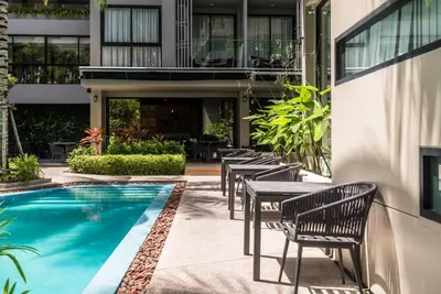 a hotel patio with tables and a swimming pool at Mountain view apartment in the heart of BangTao in Bang Tao Beach
