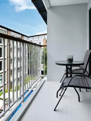 a balcony with a table and chair on a building at Title V Poolside Pool View Gym Hammam in Rawai Beach