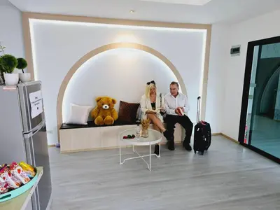 a man and woman sitting on a couch with a teddy bear at STAYHERE@AIRPORT SERVICE APARTMENT in Ban Bo Han