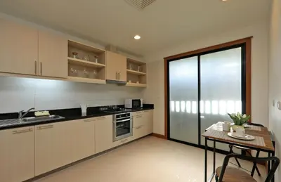 a kitchen with white cabinets and a table and a glass door at 2bdr Townhouse in Laguna Village by Capital Pro in Phuket Town