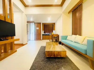 a living room with a blue couch and a table at Aonang Suite Pool Villa in Ao Nang Beach