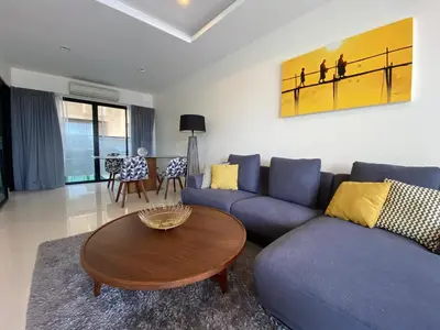 a living room with a blue couch and a wooden table at 2 bdr Townhouse in Laguna Park by CapitalPro in Phuket Town