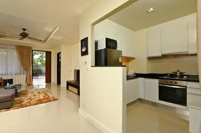 a kitchen with white cabinets and a living room at 3bdr Townhouse Laguna Park Bangtao Beach by CapitalPro in Phuket Town