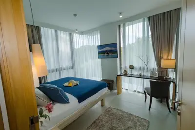 a bedroom with a blue bed and a desk and window at 2bdr Apartment Oceanstone Laguna by Capital Pro in Phuket Town