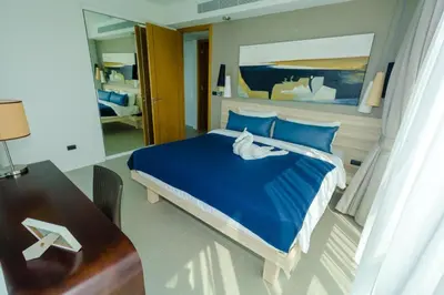 a bedroom with a large blue bed and a desk at 2bdr Apartment Oceanstone Laguna by Capital Pro in Phuket Town