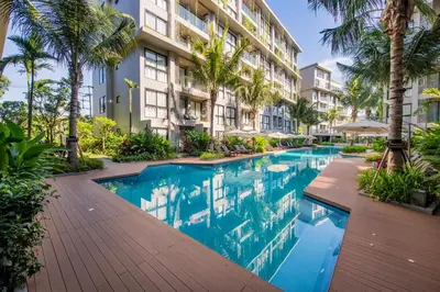a swimming pool in front of a building with palm trees at 1bdr Cozy apartment in Diamond Resort Bangtao Beach by Capital Pro in Phuket Town