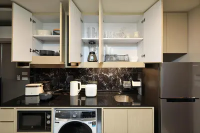 a kitchen with white cabinets and a washing machine at 1 bdr Sea view Apartment in Mida Surin Beach by Capital Pro in Phuket Town