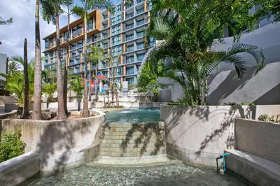a swimming pool in front of a building with palm trees at 1 bdr Sea view Apartment in Mida Surin Beach by Capital Pro in Phuket Town