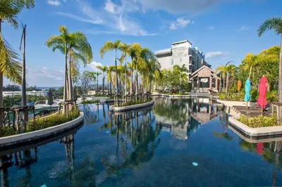 a pool of water with palm trees and a building at 1 bdr Sea view Apartment in Mida Surin Beach by Capital Pro in Phuket Town